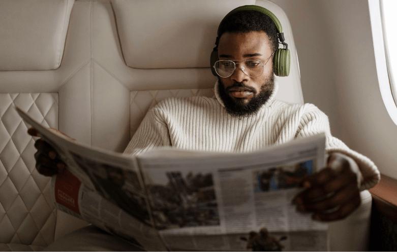 man reading newspaper with headphones